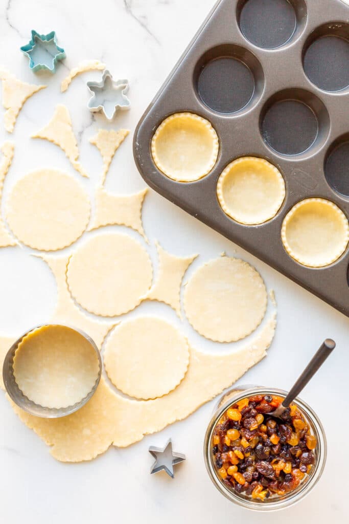 Assembling mince pies in muffin tins.