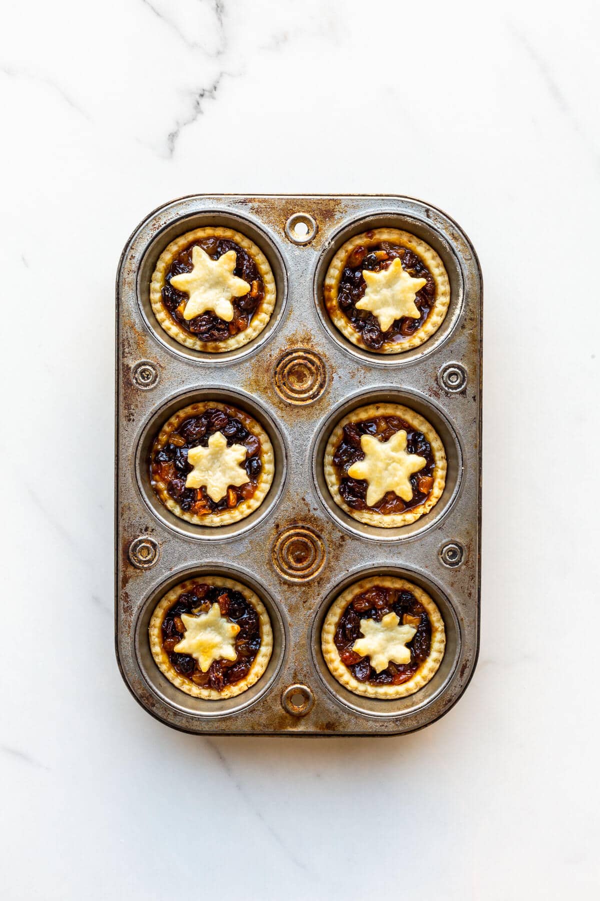 Freshly baked mincemeat tarts in a muffin tin, ready to unmould and serve.