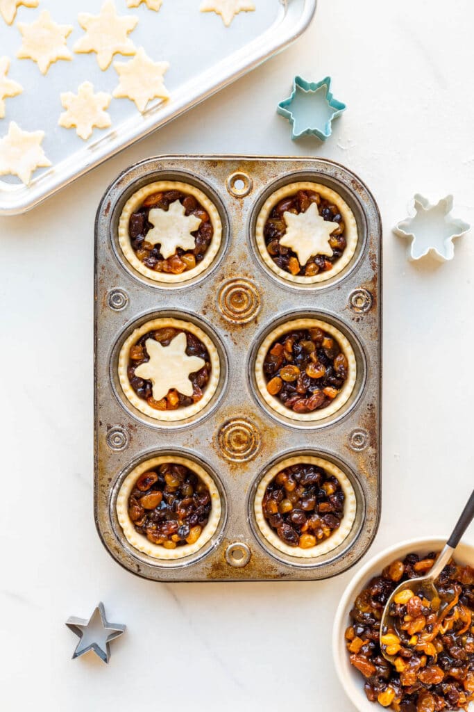 Assembling mince pies in muffin tins.