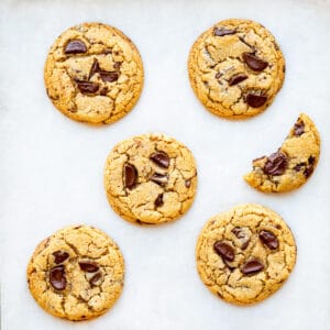 Thick and chewy chocolate chip cookies on parchment paper.