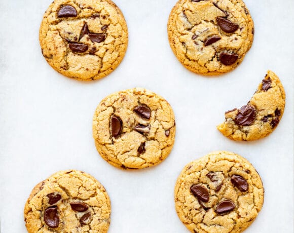 Thick and chewy chocolate chip cookies on parchment paper.