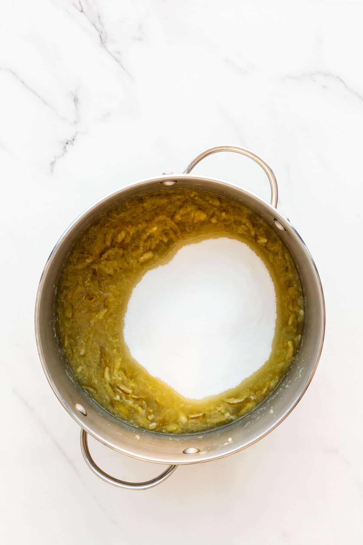 Combining boiled sliced limes with sugar and lemon juice in a big pot to make marmalade.