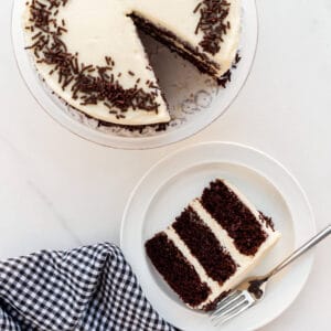 Chocolate layer cake with cream cheese frosting and chocolate sprinkles being served on plates.