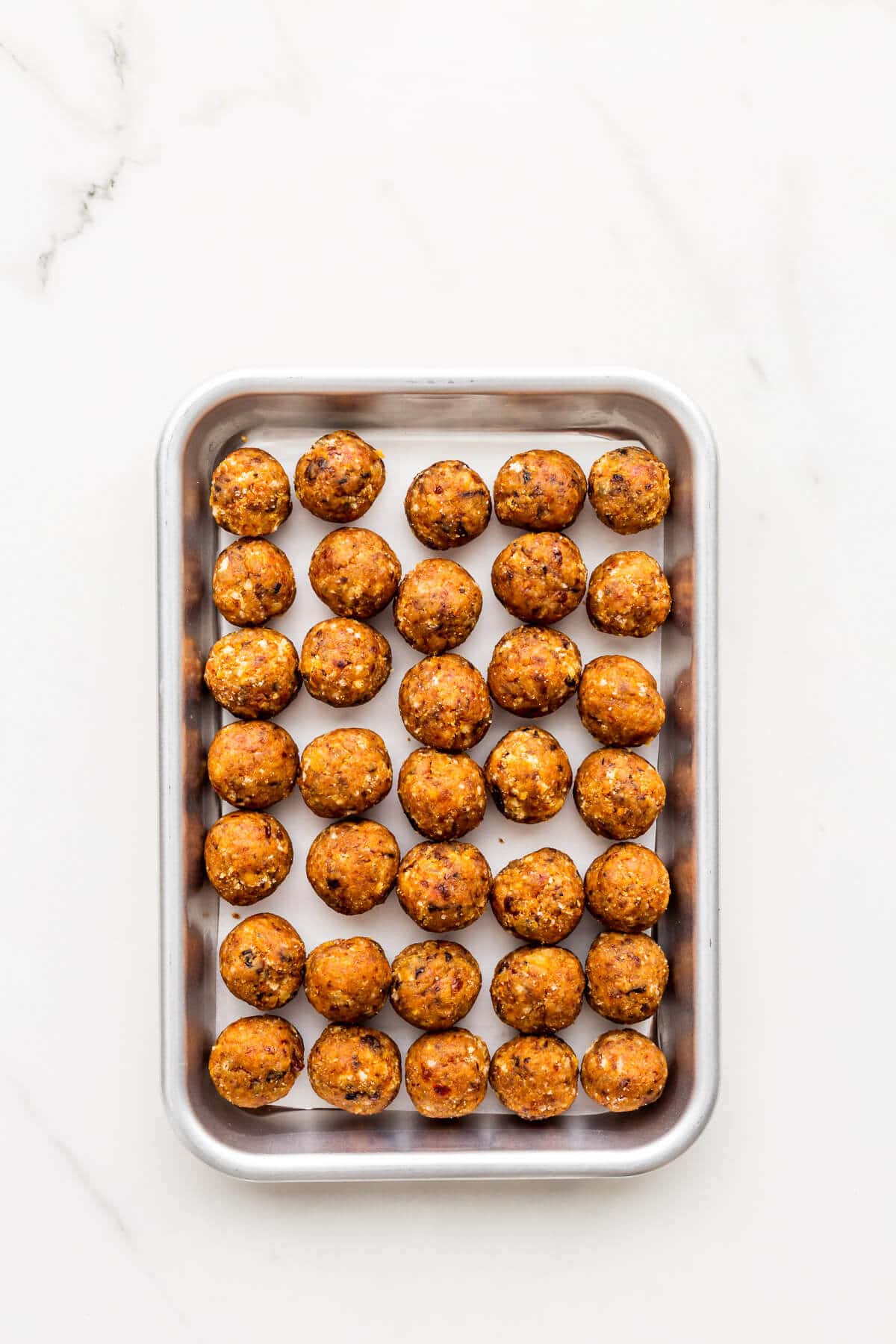 Christmas cake balls scooped onto a sheet pan and ready to be dipped in melted white chocolate