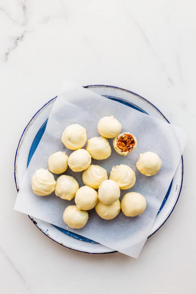 A plate of Christmas cake balls dipped in white chocolate and ready to be eaten.