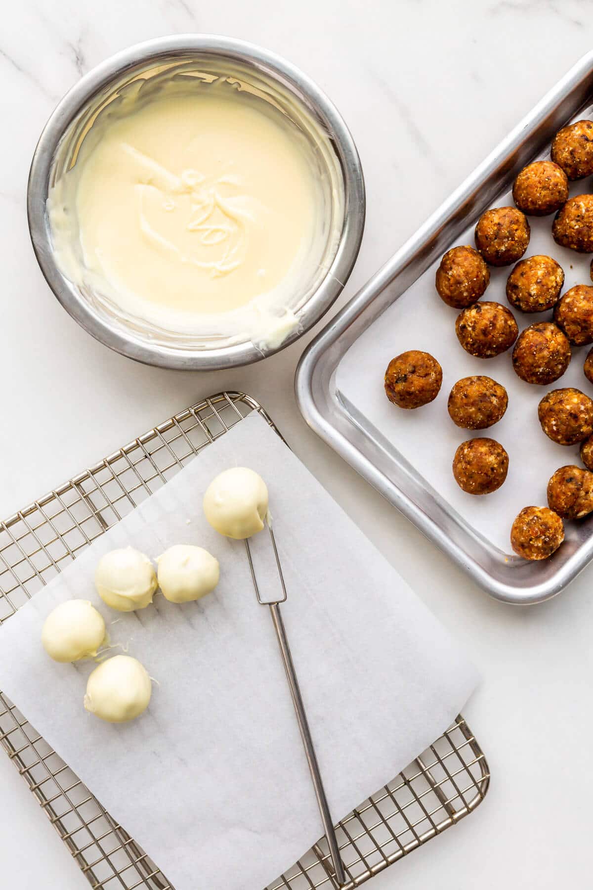 Dipping Christmas cake balls in melted white chocolate to coat them.