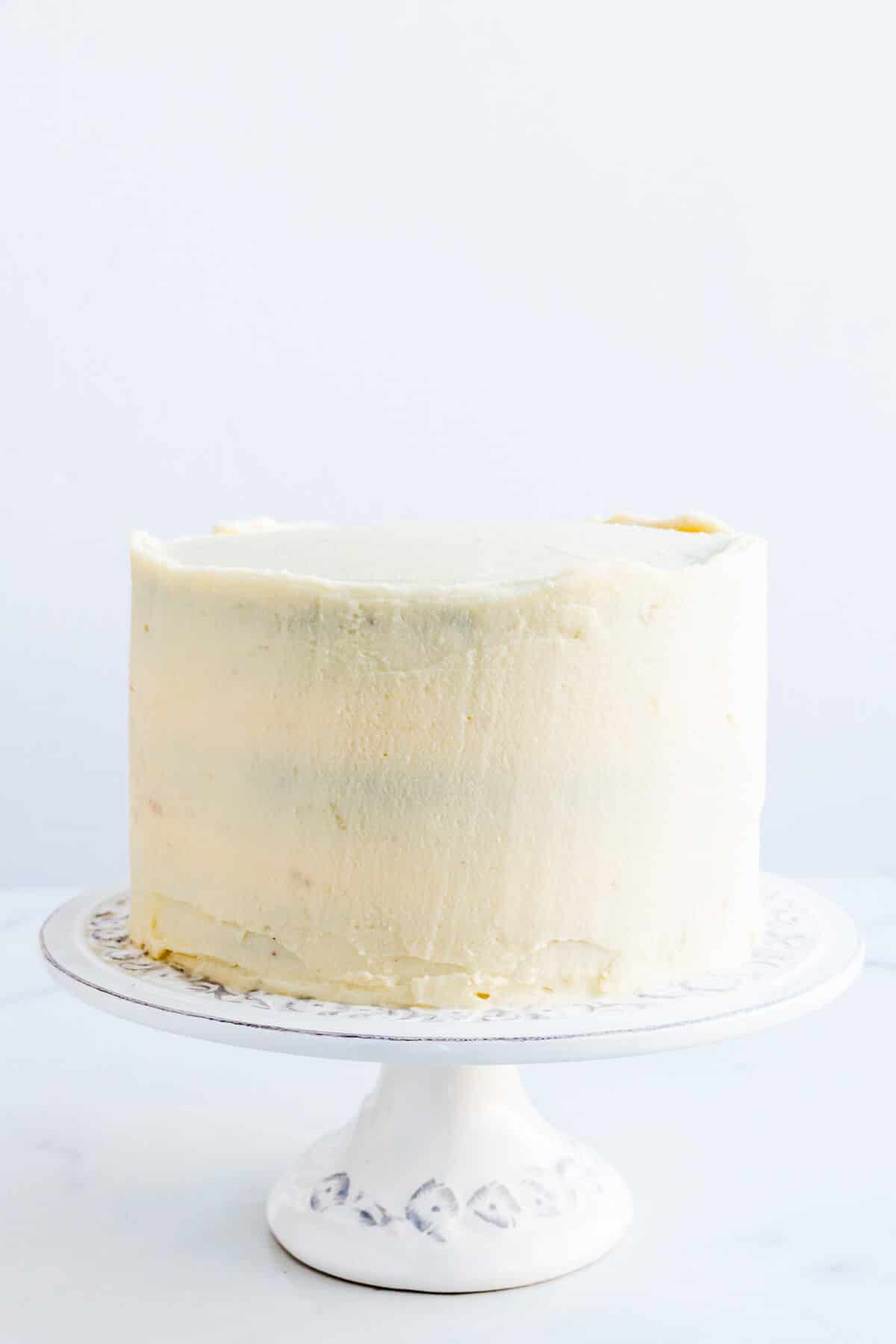 Chocolate cake with cream cheese frosting on a cake stand.