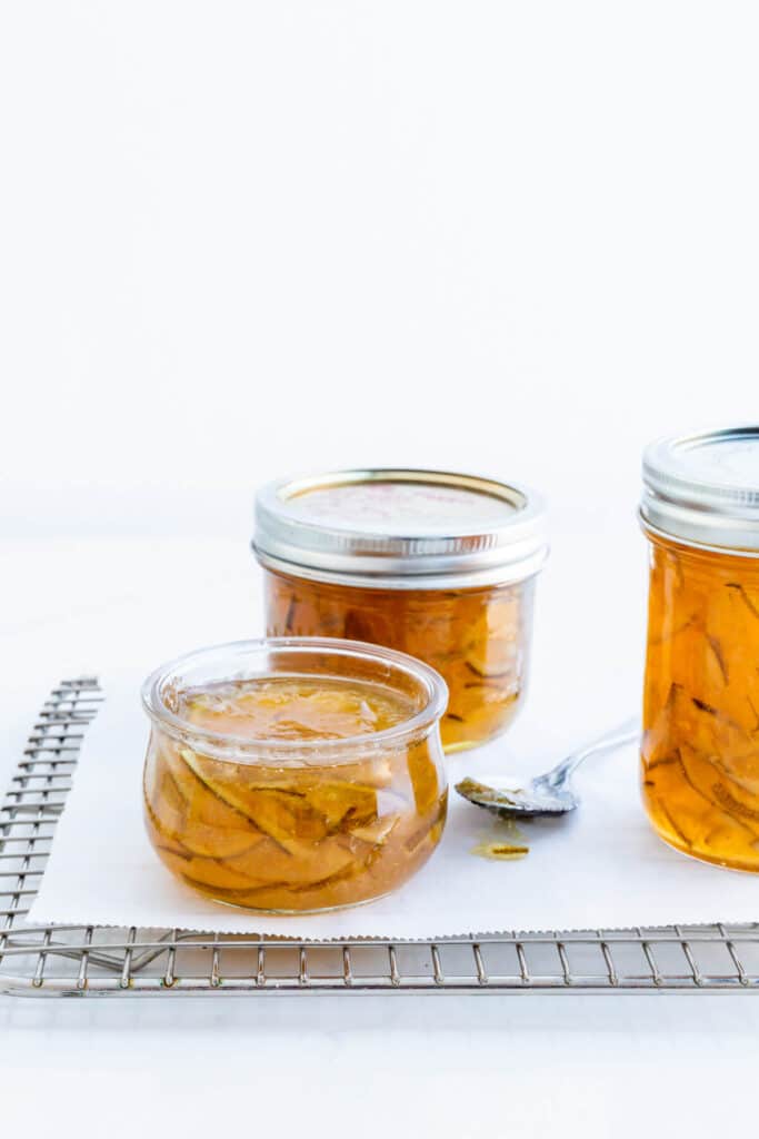 Jars of homemade lime marmalade on a cooling rack.