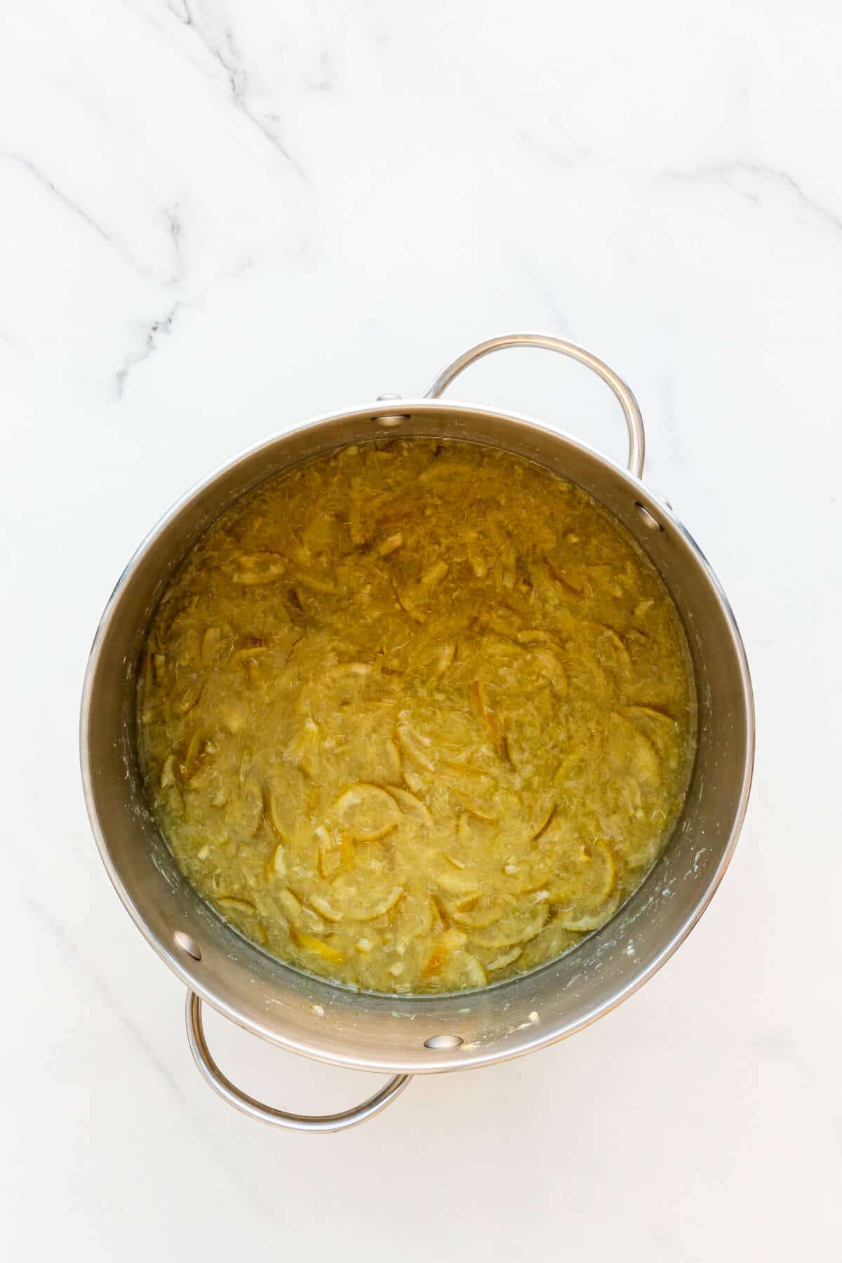 Lime slices boiled in a pot until translucent and very soft to make marmalade.