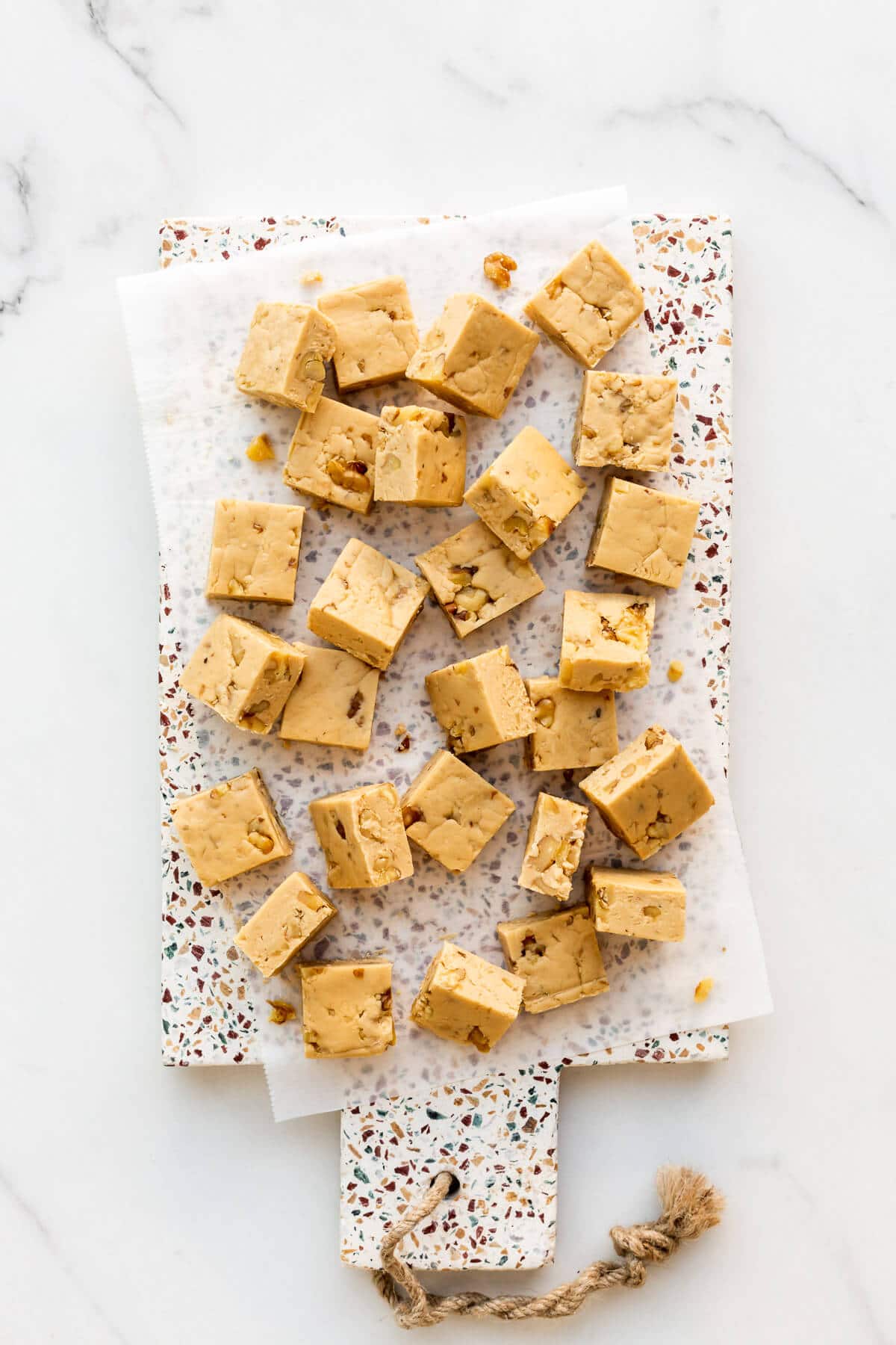 Maple fudge with walnuts, cut into squares, on a platter.