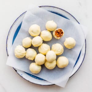 White chocolate-covered fruitcake balls on a plate, ready to be eaten.