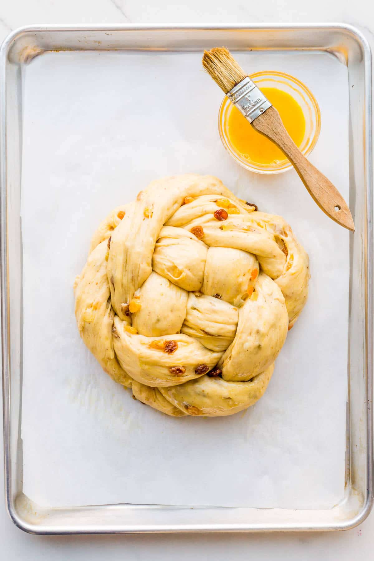 Brushing the surface of a braided boule with egg wash before baking.