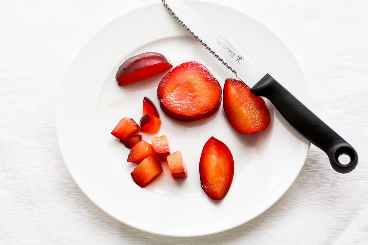 Chopping fresh plums on a plate to add to muffins.