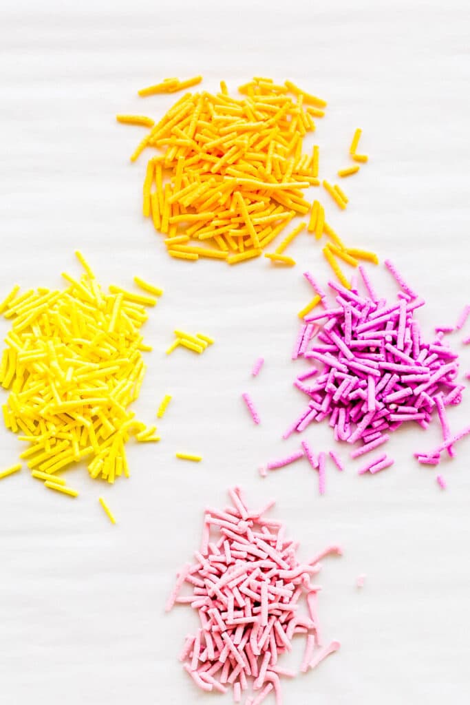 Small piles of colourful homemade sprinkles on parchment paper.