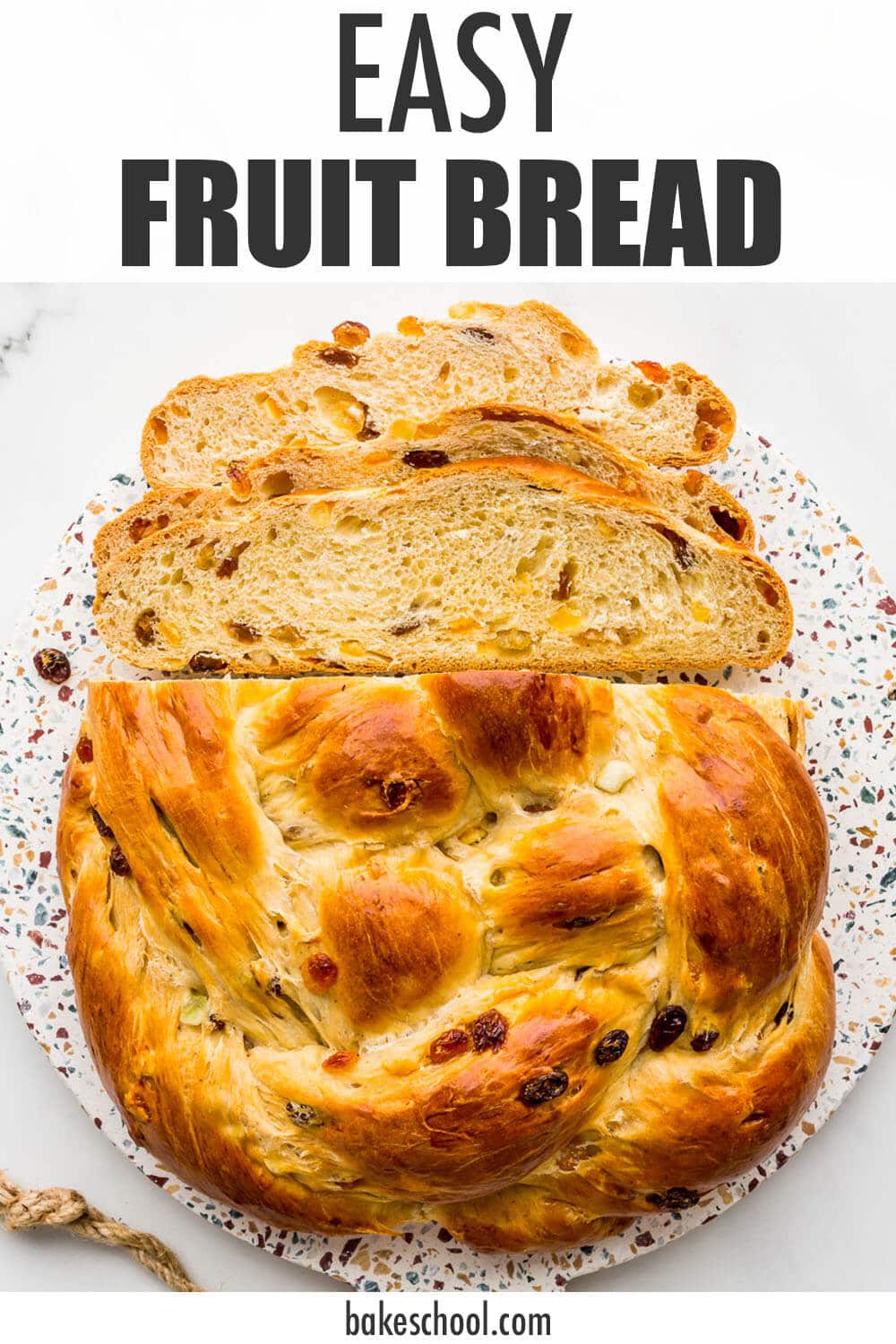 Braided fruit bread, sliced on a board.