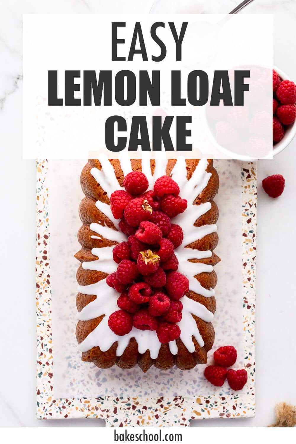 Iced lemon loaf cake on a terrazzo board.