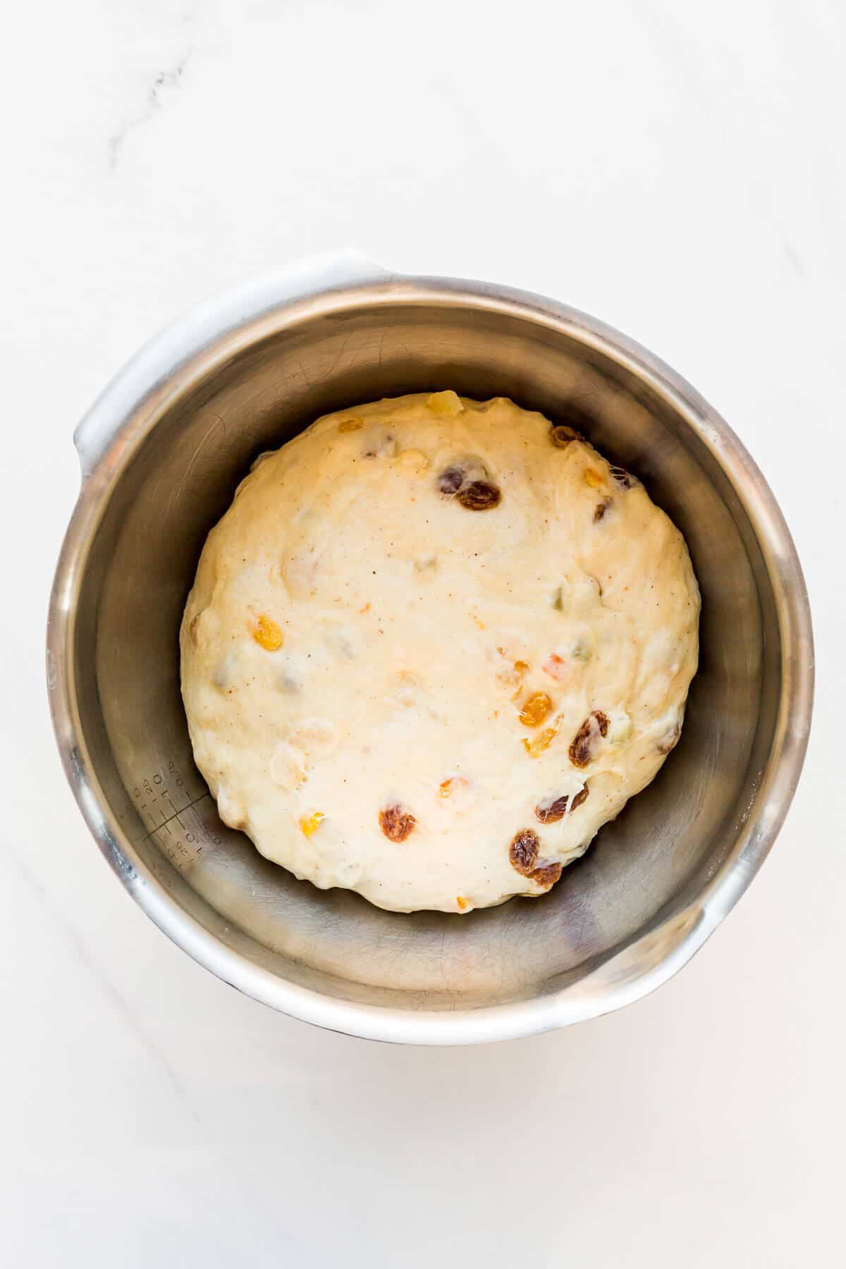 Fruit bread dough with raisins in a bowl, rising.