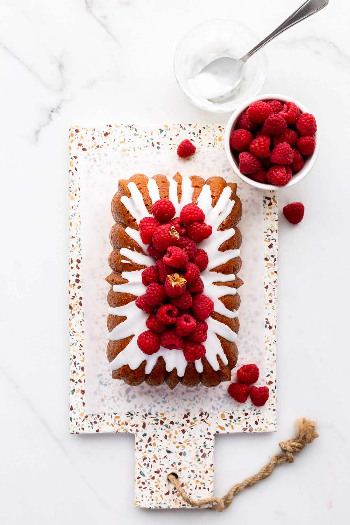 Lemon drizzle cake topped with icing and fresh raspberries.