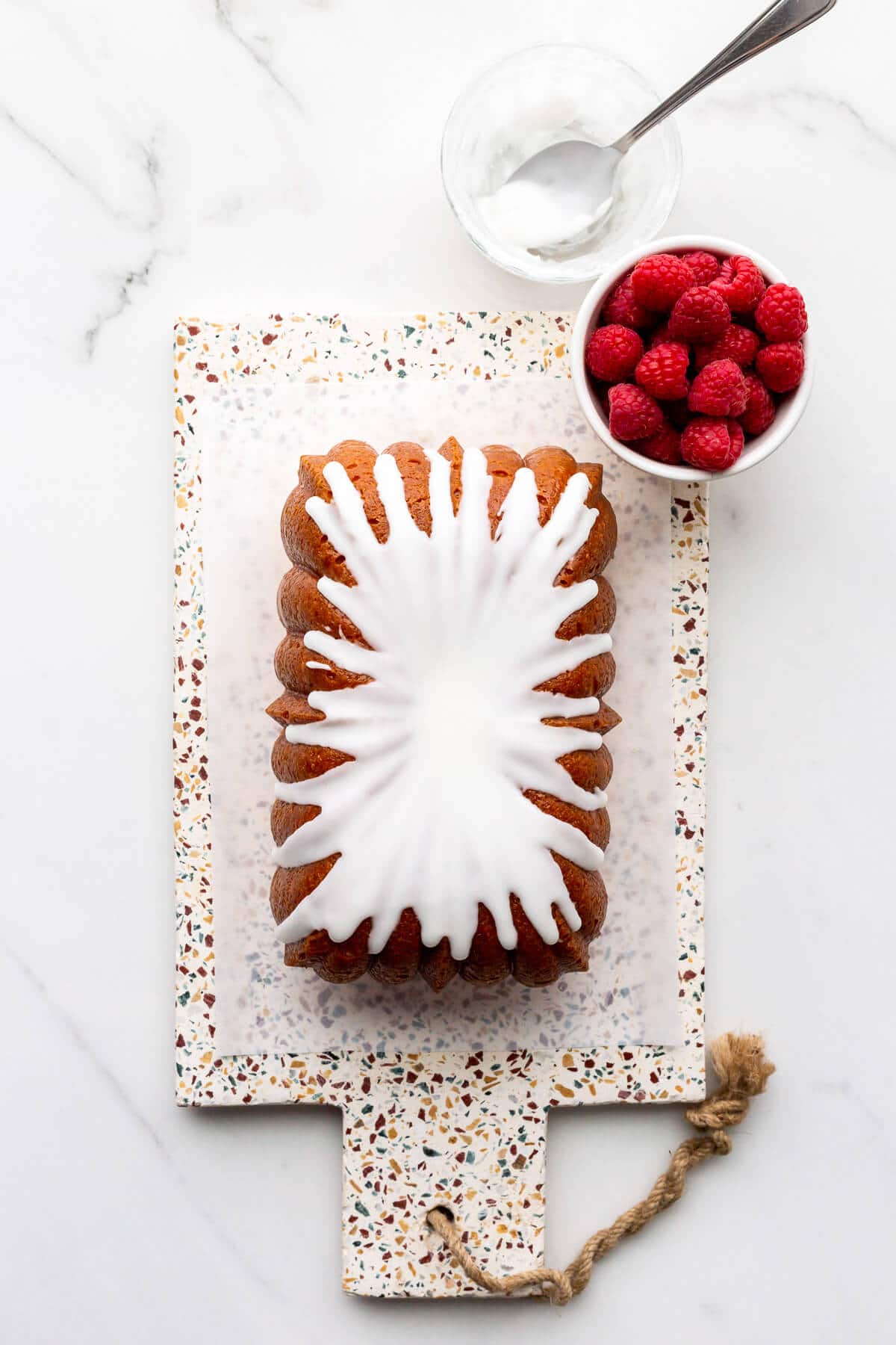 Drizzling simple icing on a lemon loaf cake before serving.