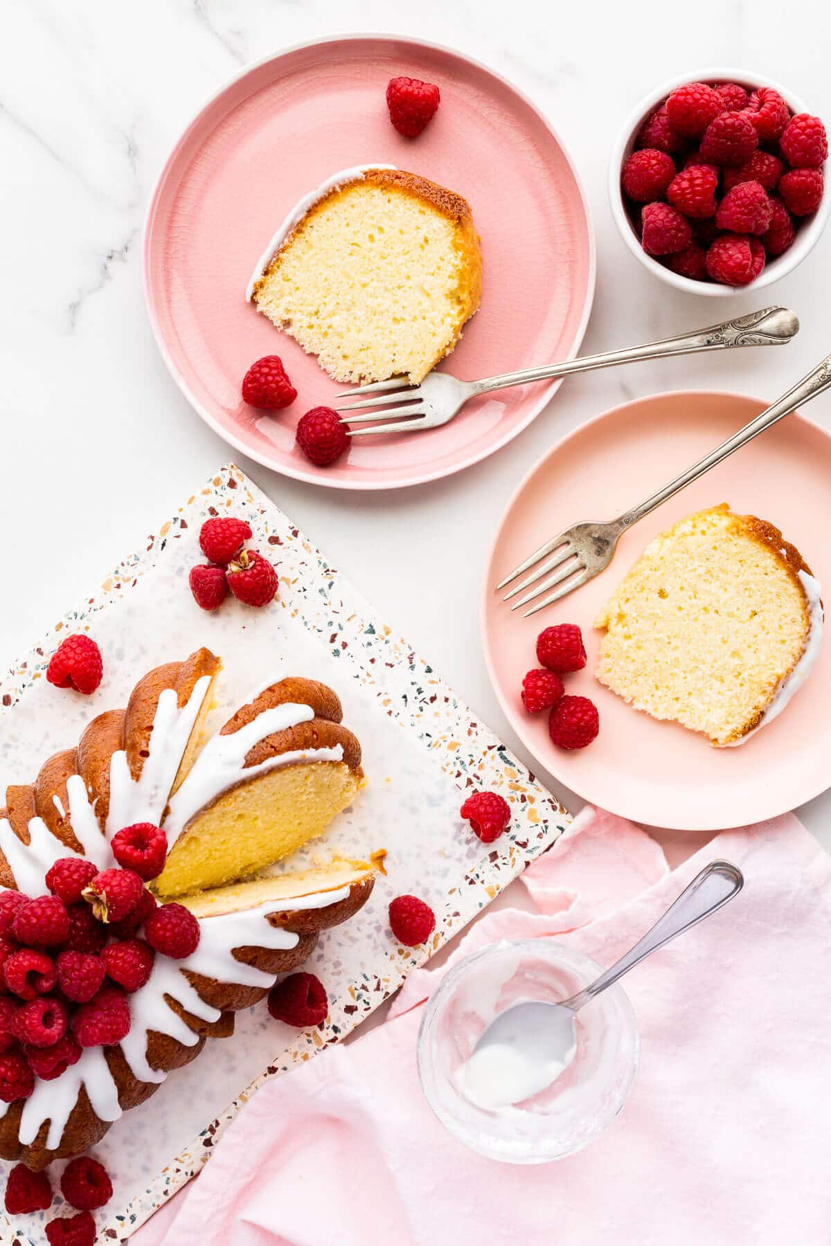 Slices of lemon bread on pink plates, served with raspberries.
