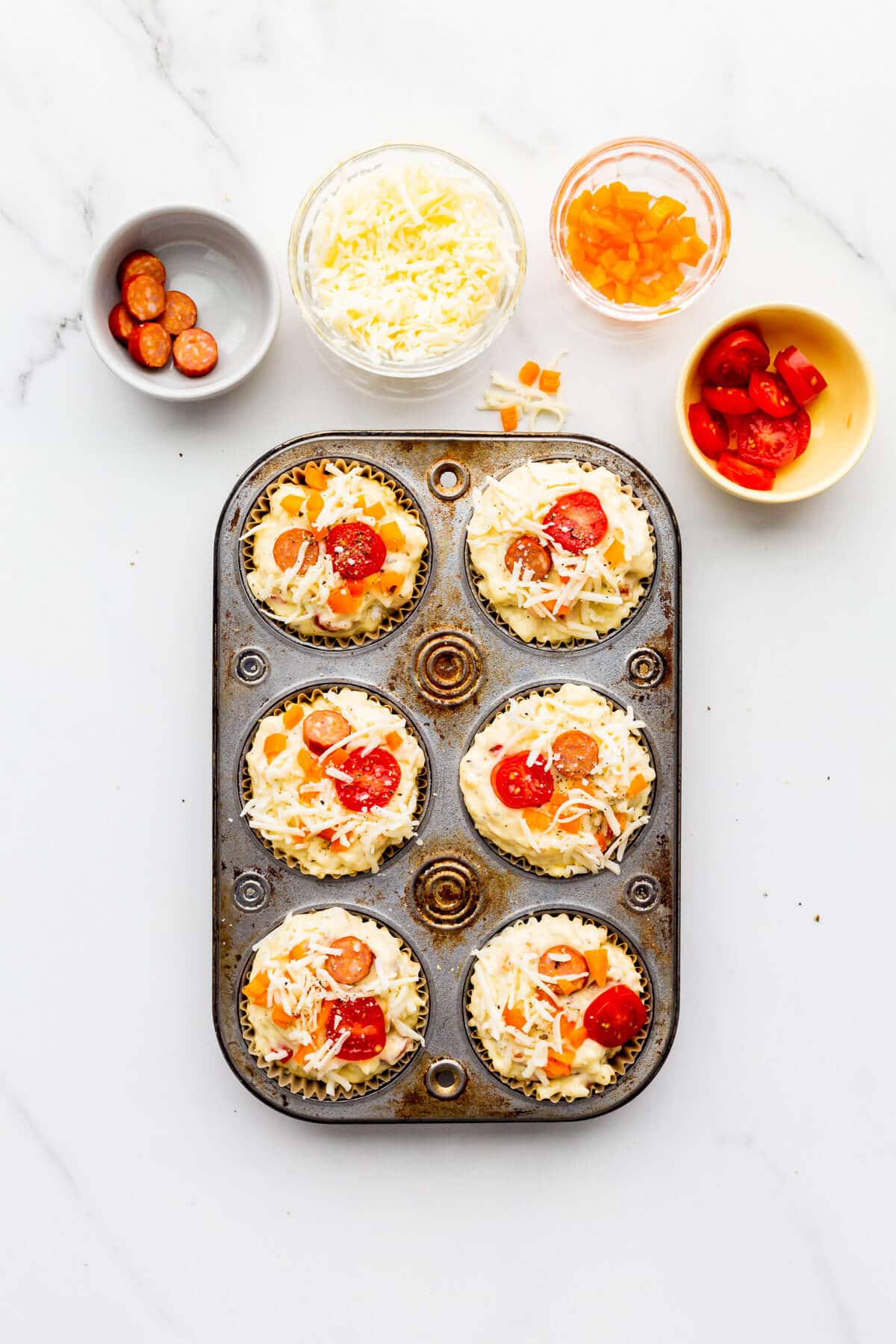 Pizza muffins with all the toppings before baking.