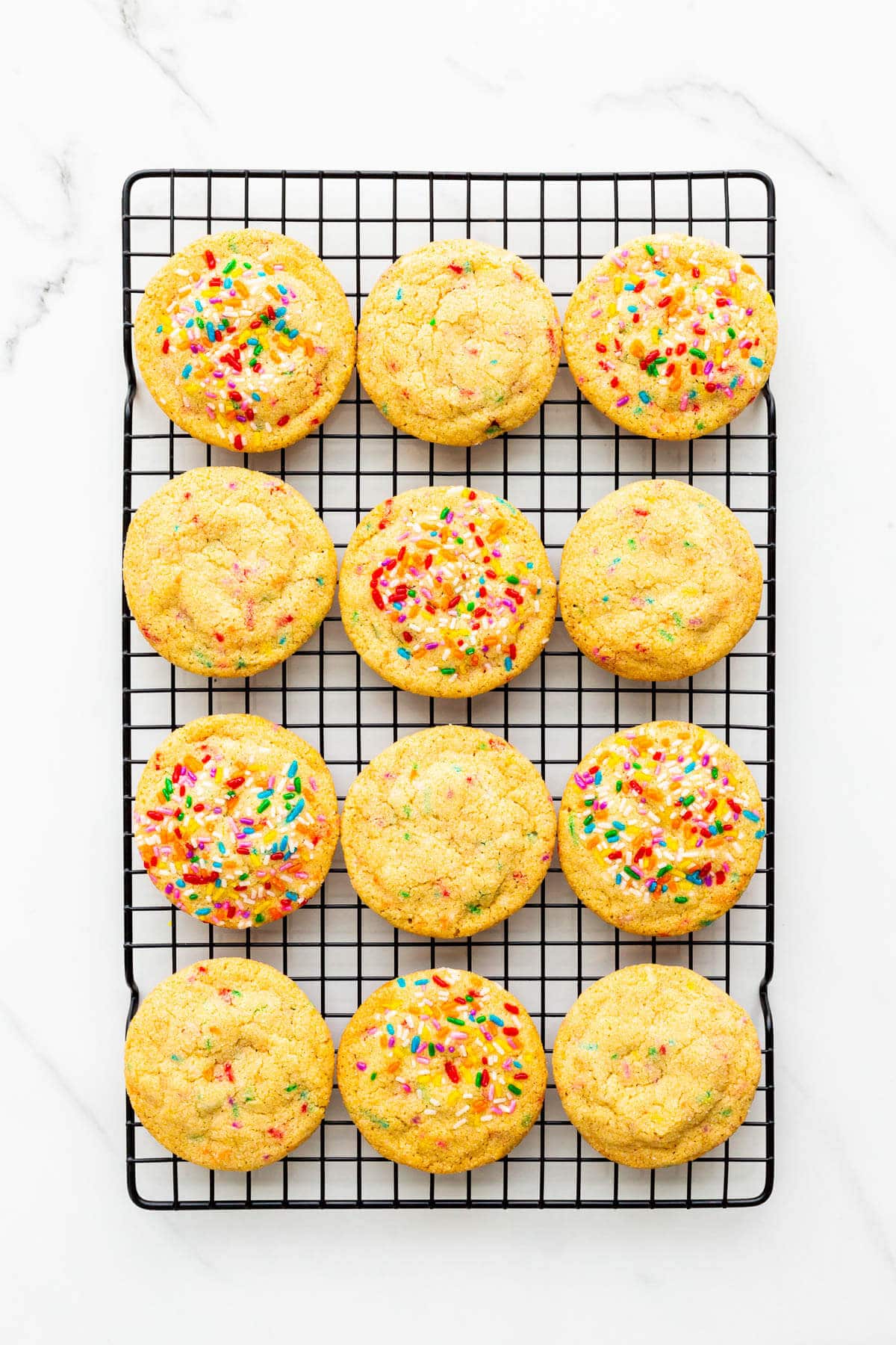 Sprinkle sugar cookies on a cooling rack.