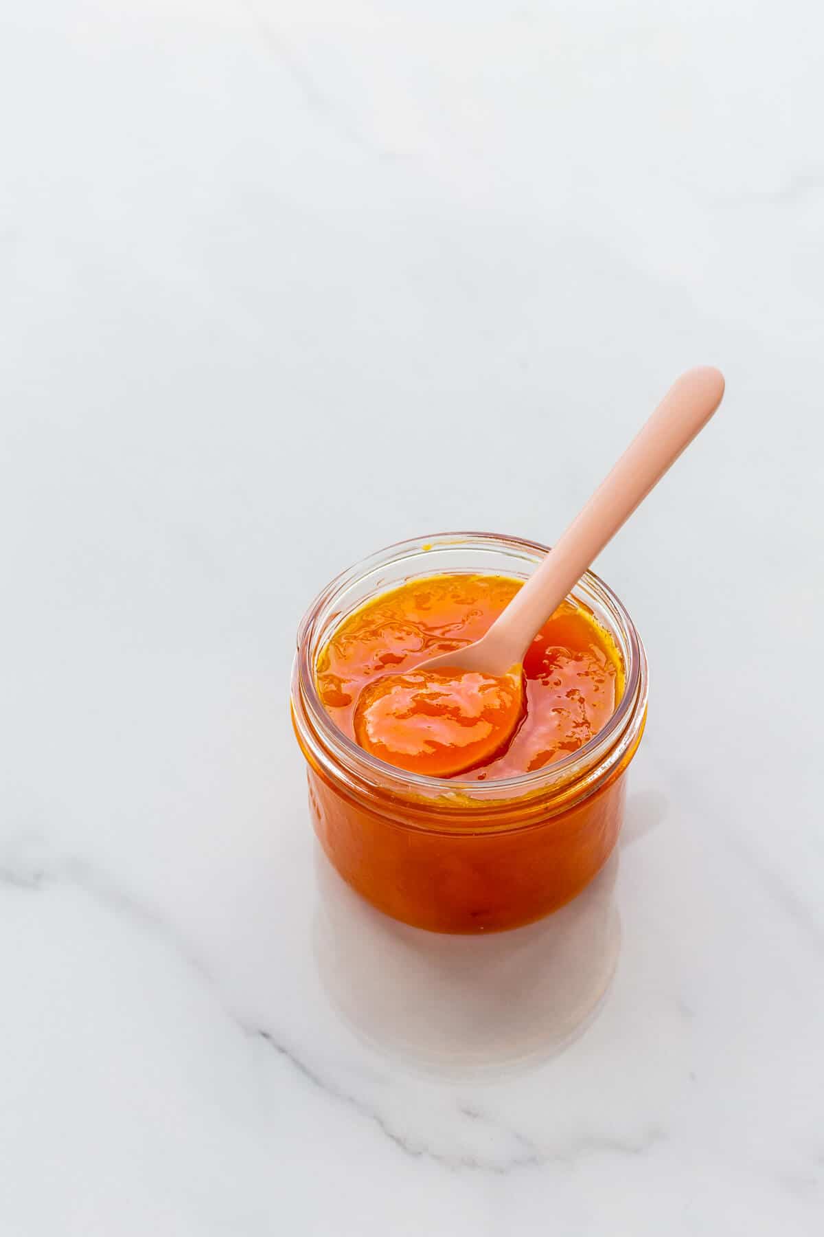 A jar of apricot jam with a spoon.