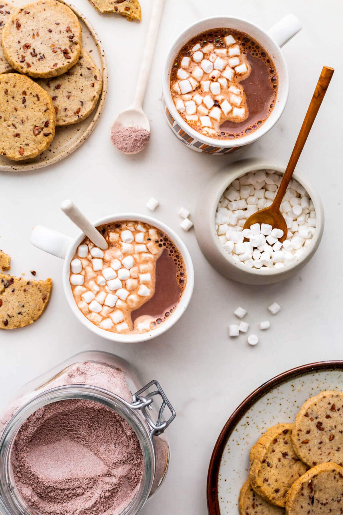 Cups of hot cocoa made from homemade mix with mini marshmallows and cookies.