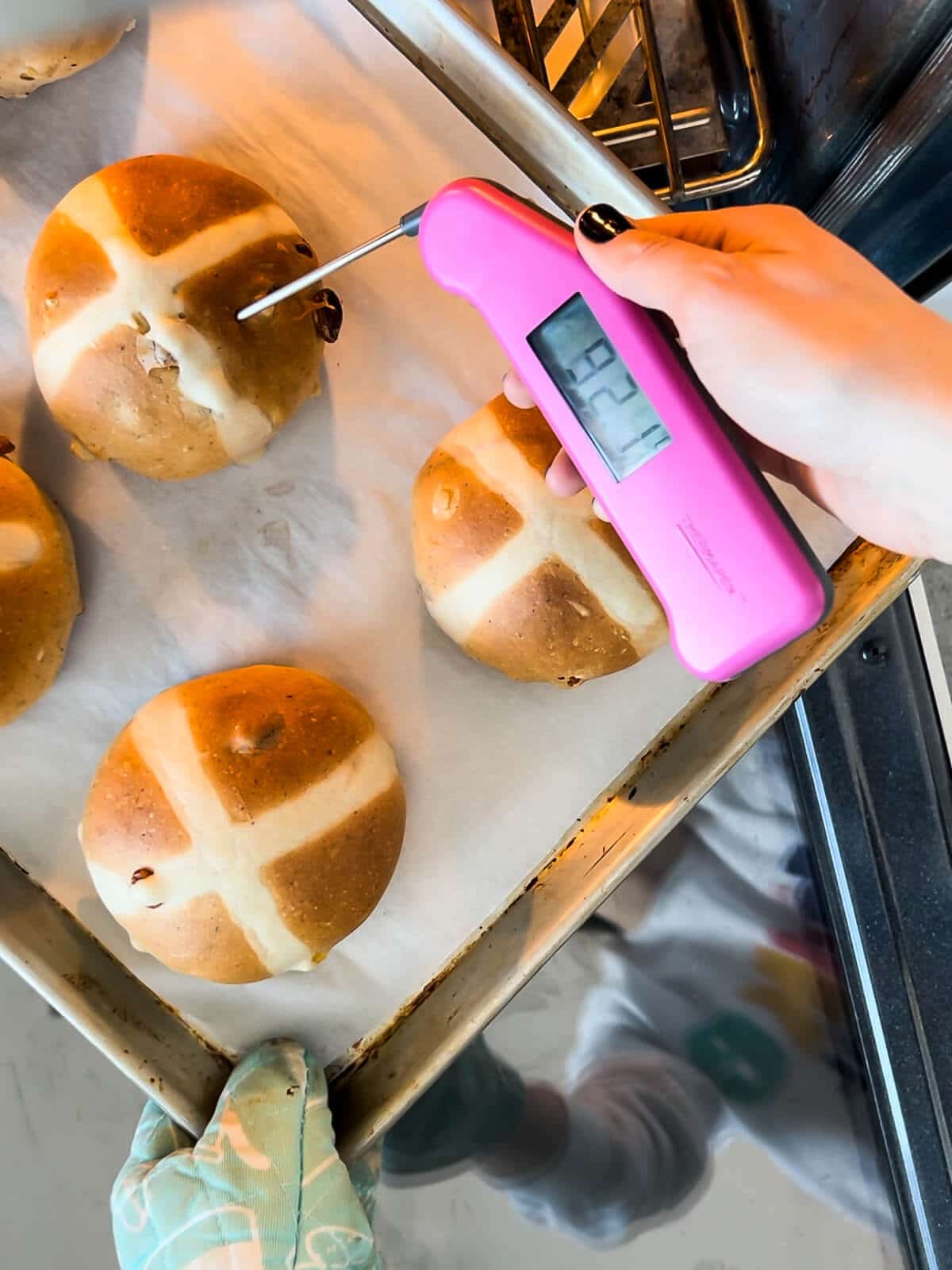 Using a digital thermometer to check the internal temperature of hot cross buns to make sure they are baked through before taking them out of the oven.