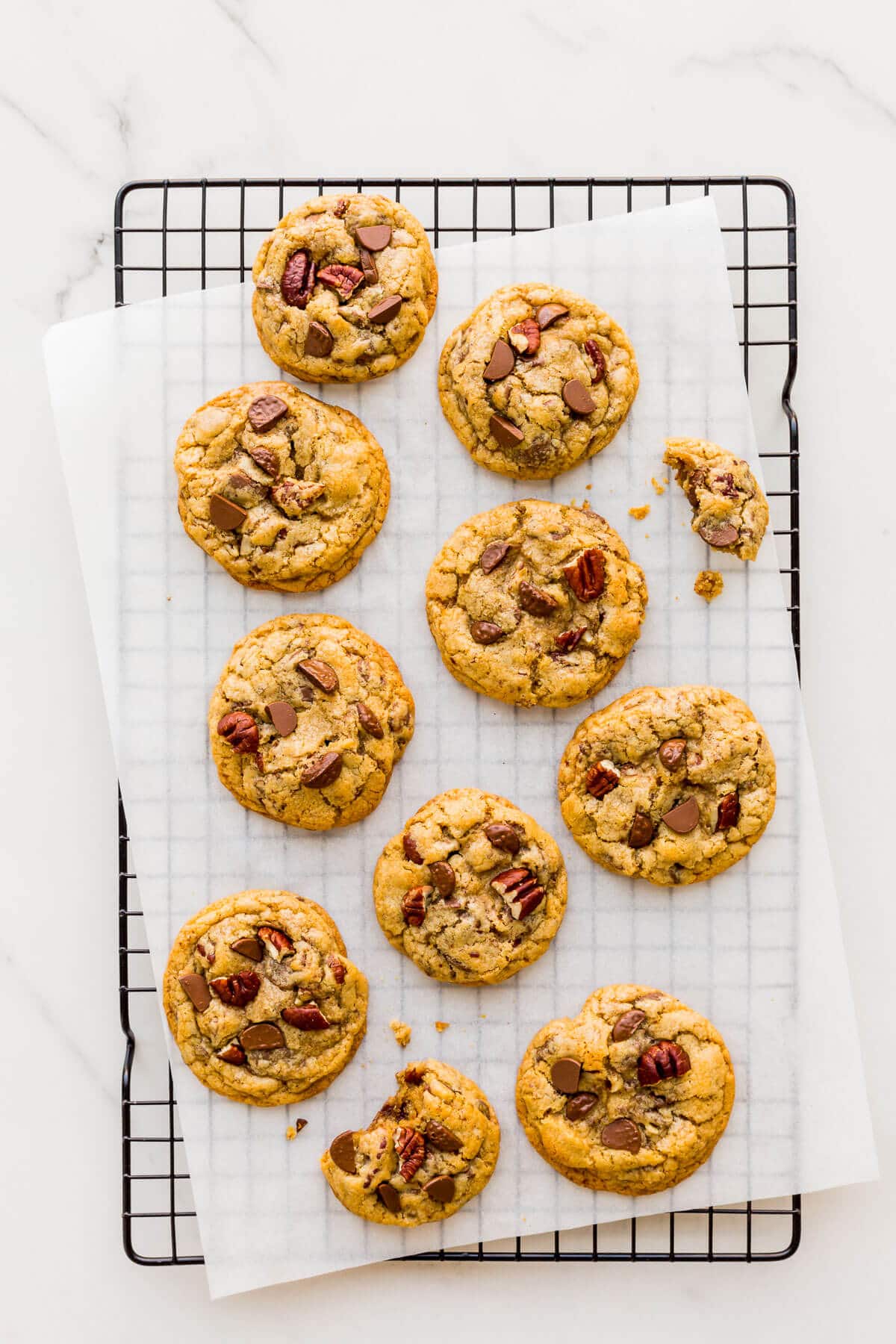 Chocolate chip cookies with pecans cooling on a wire rack.