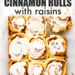 A dozen cinnamon rolls topped with cream cheese icing unmoulded and ready to eat.