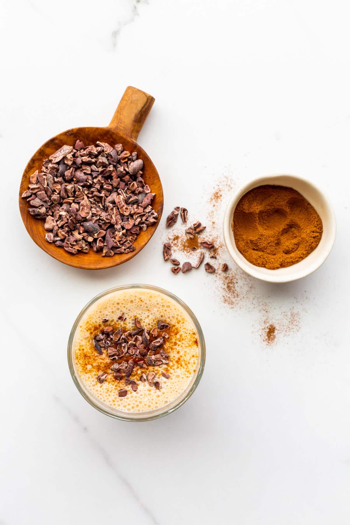 Garnishing banana smoothies with cocoa nibs and espresso powder to serve them.
