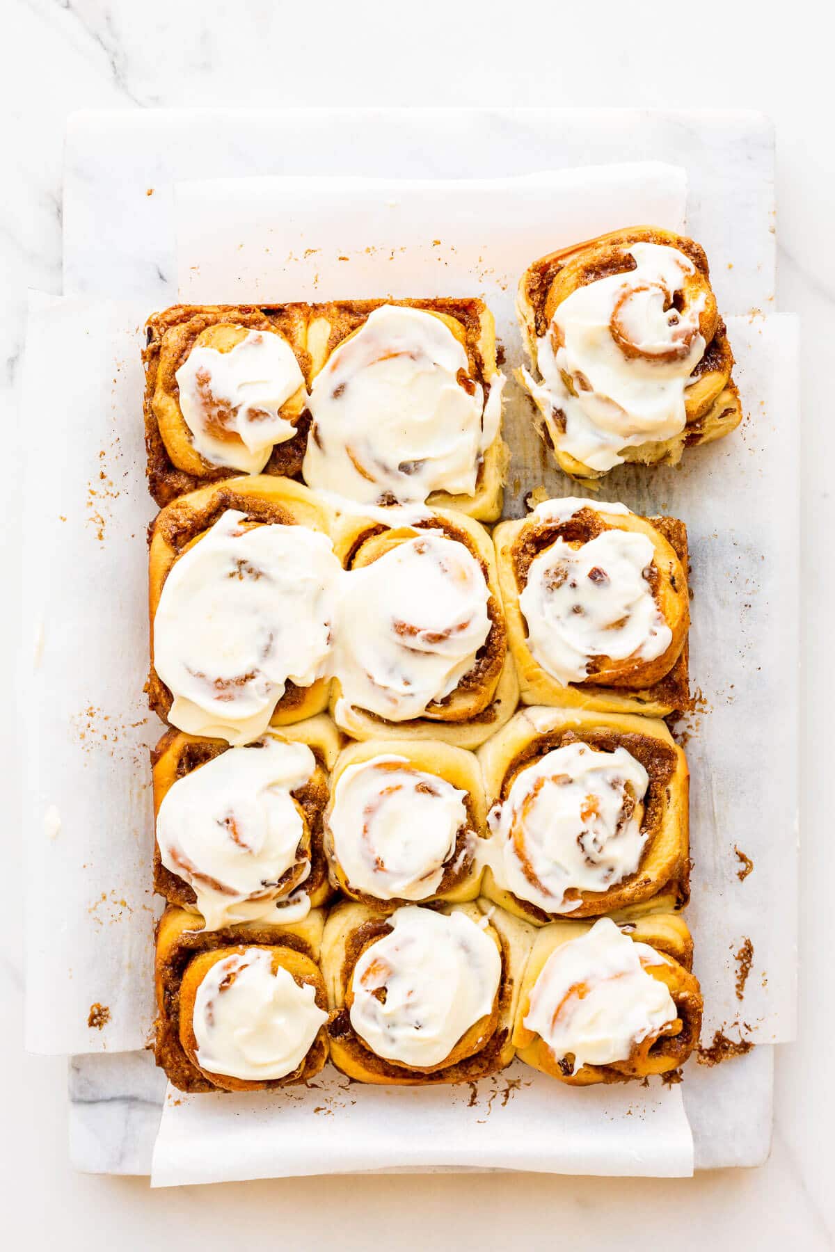 Freshly baked cinnamon rolls with raisins topped with cream cheese icing.