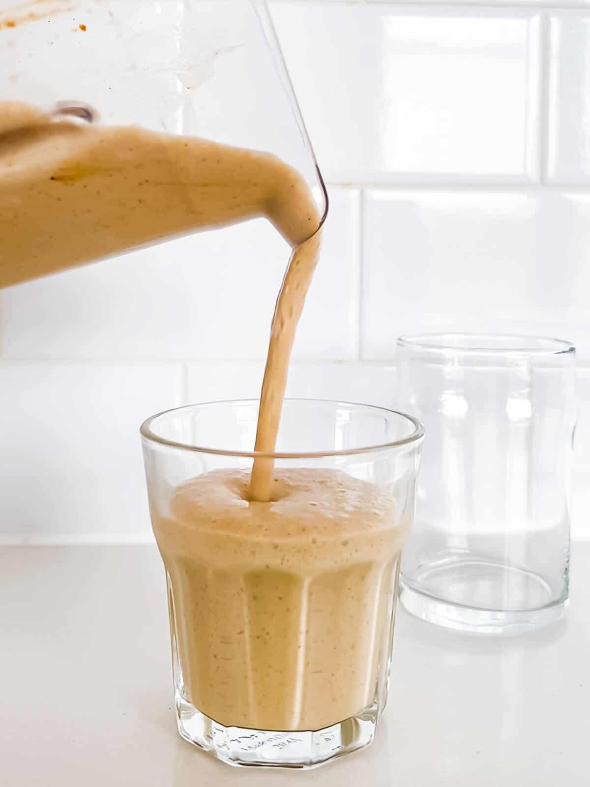 Pouring a banana coffee smoothie into small glasses to serve.