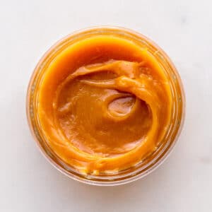 A jar of homemade milk jam viewed from the top to show the gooey, thick texture.