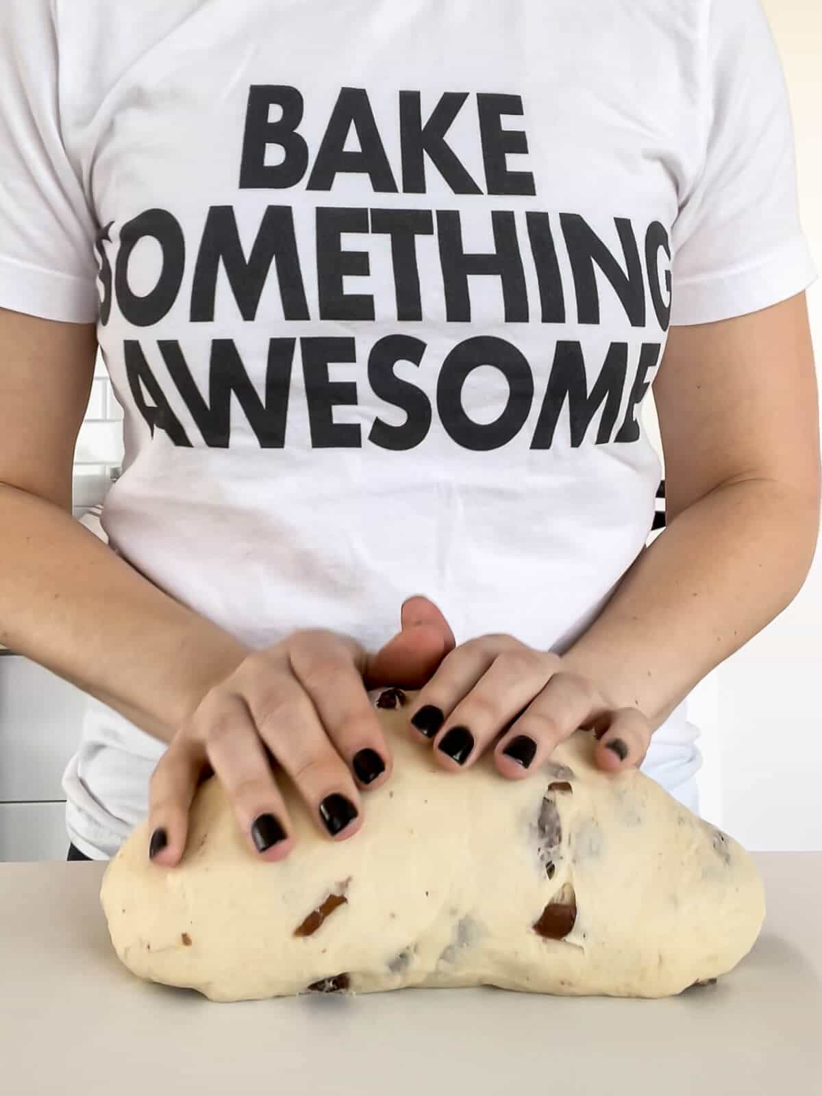 Kneading dough with raisins by hand on a clean counter before transferring to a bowl to rise.