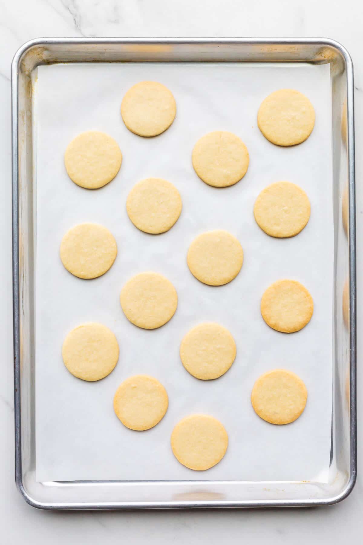 Freshly baked shortbread cookie cutouts on a sheet pan.
