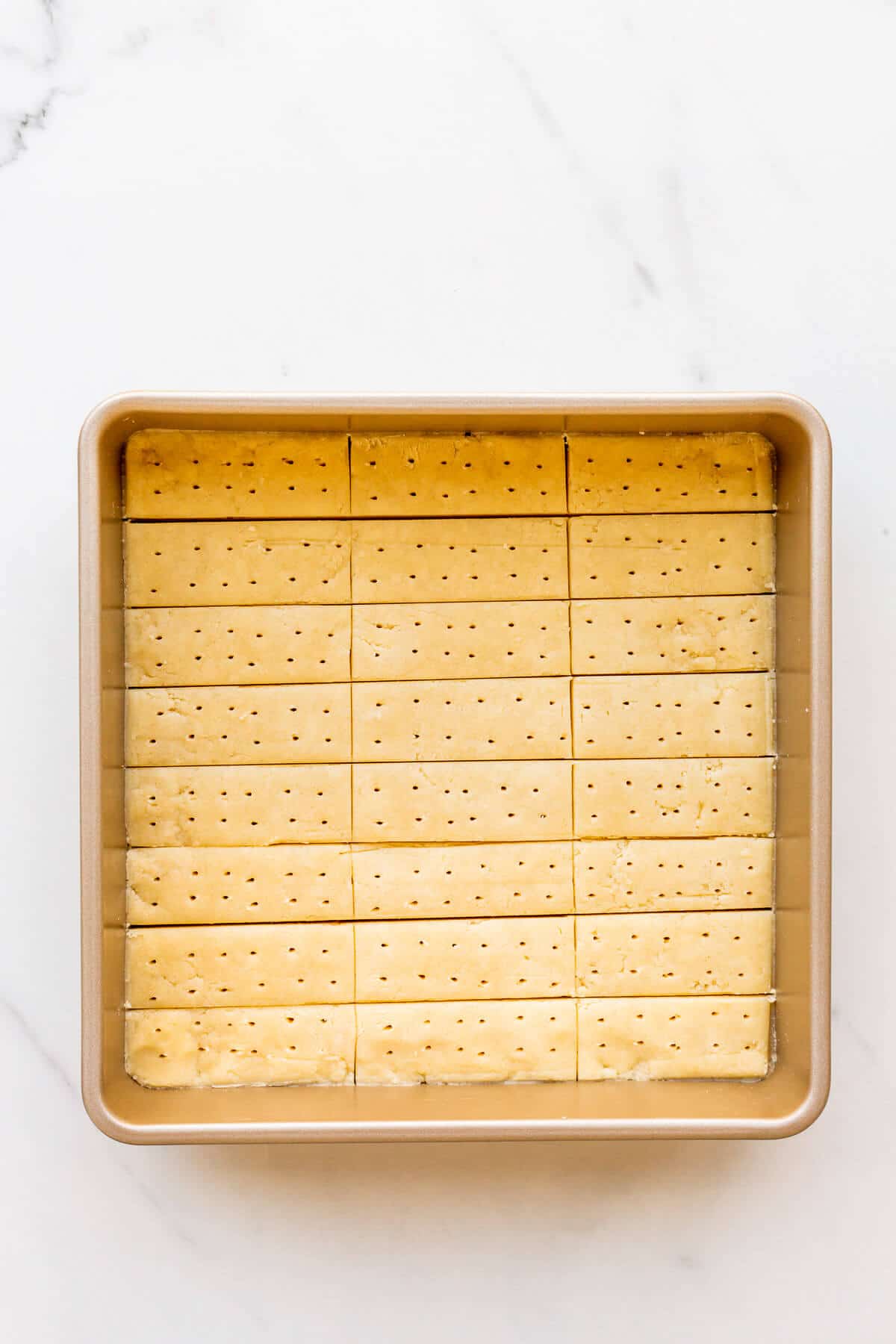 Shortbread cookies cut into sticks in a square pan before baking.