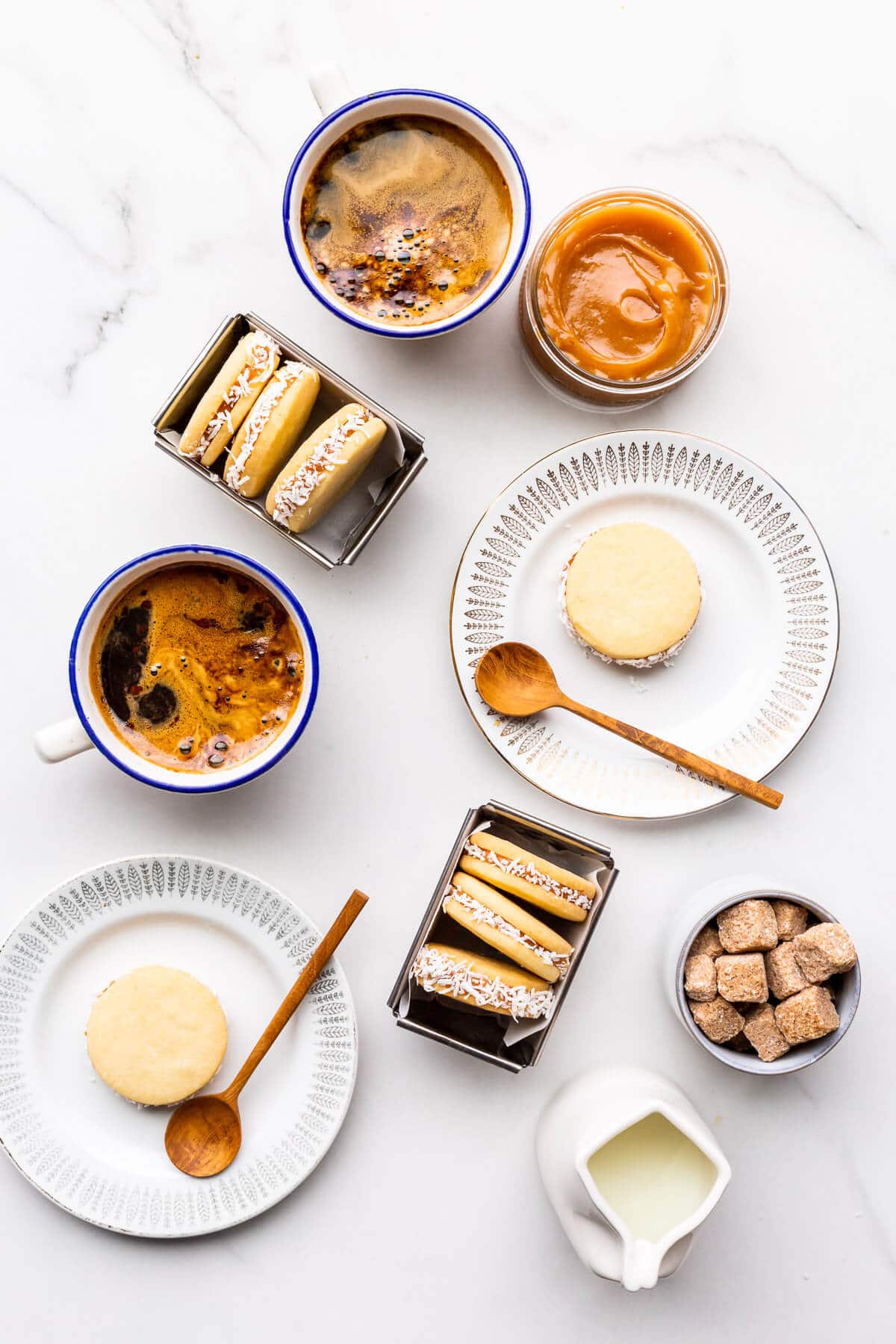 Homemade alfajores cookies on plates served with coffee.