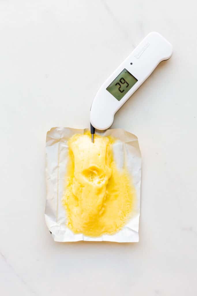 Taking the temperature of butter that is too warm to bake with and that is partially melted.