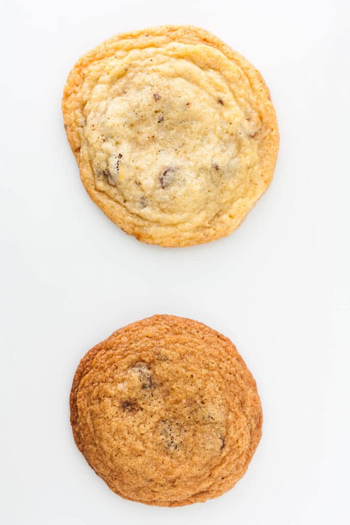 Two chocolate chip cookies: one is more spread out and paler in colour and the other is darker and more compact.