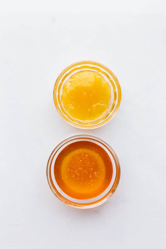 Two bowls of honey for comparison: crystallized honey which is more opaque and with visible sugar crystals suspended, and liquid honey which is fluid, thick, and golden in colour.