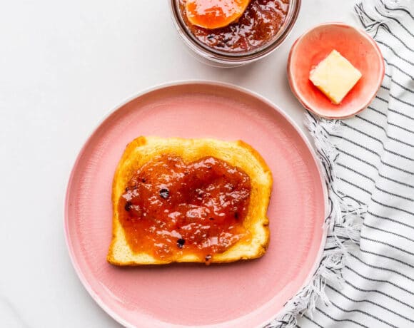 A pink plate with a piece of toast topped with homemade rhubarb jam.
