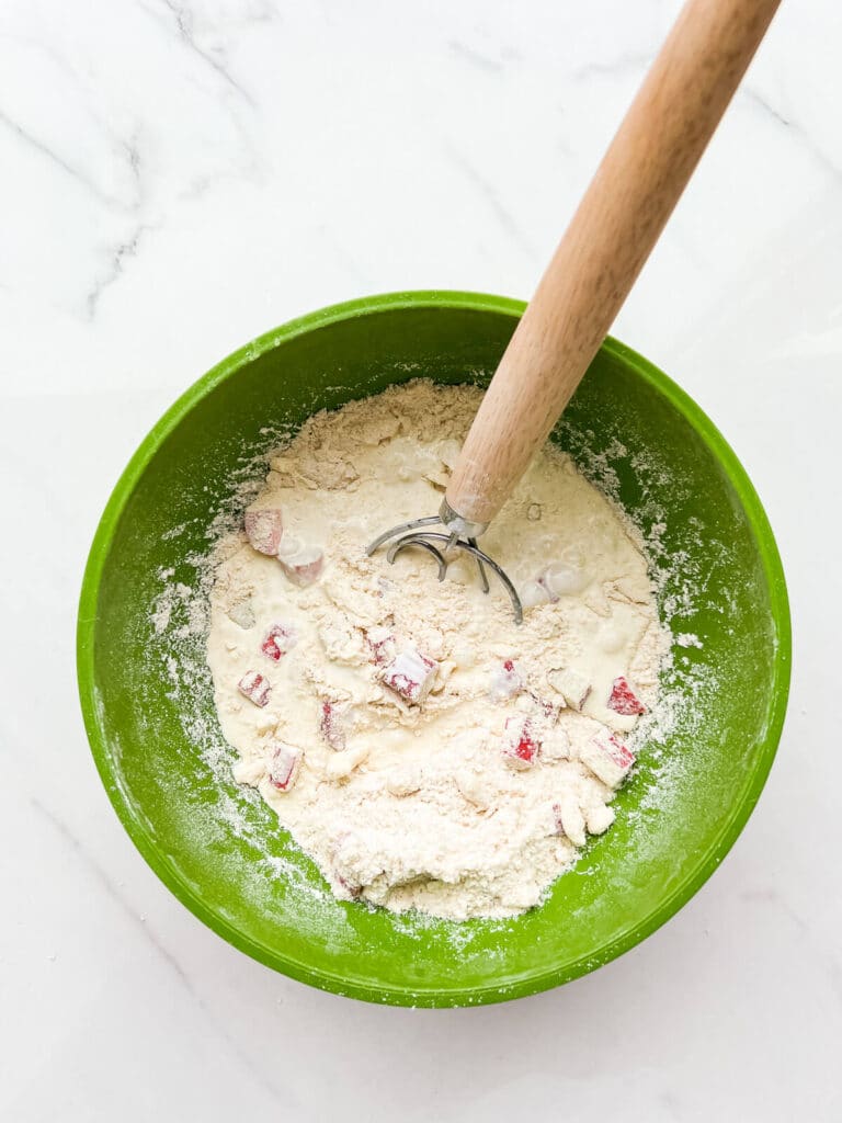 Incorporating cream with dry ingredients and butter to make scones with rhubarb.