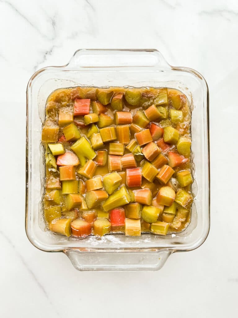 A glass baking dish with roasted rhubarb in a syrup.