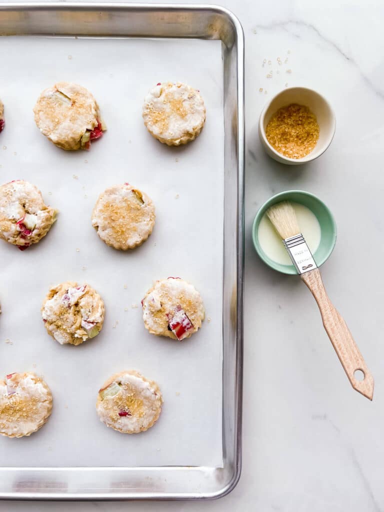 Brushing scones with cream and sprinkling with turbinado sugar before baking.