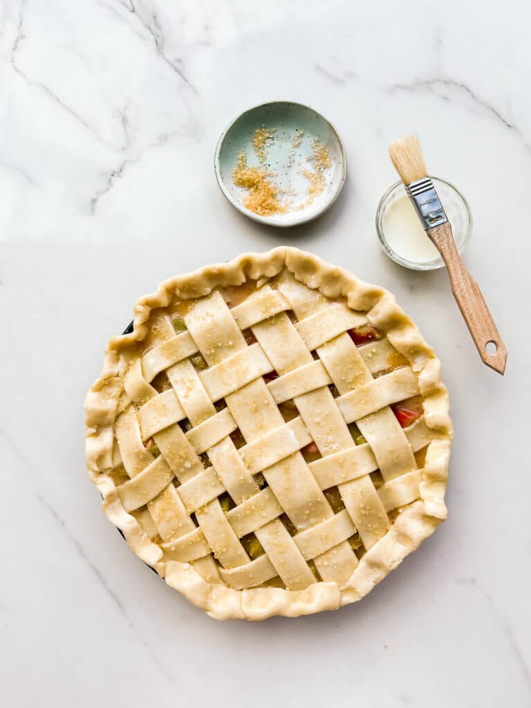 Brushing a lattice pie crust with milk and sprinkling with turbinado sugar before baking.