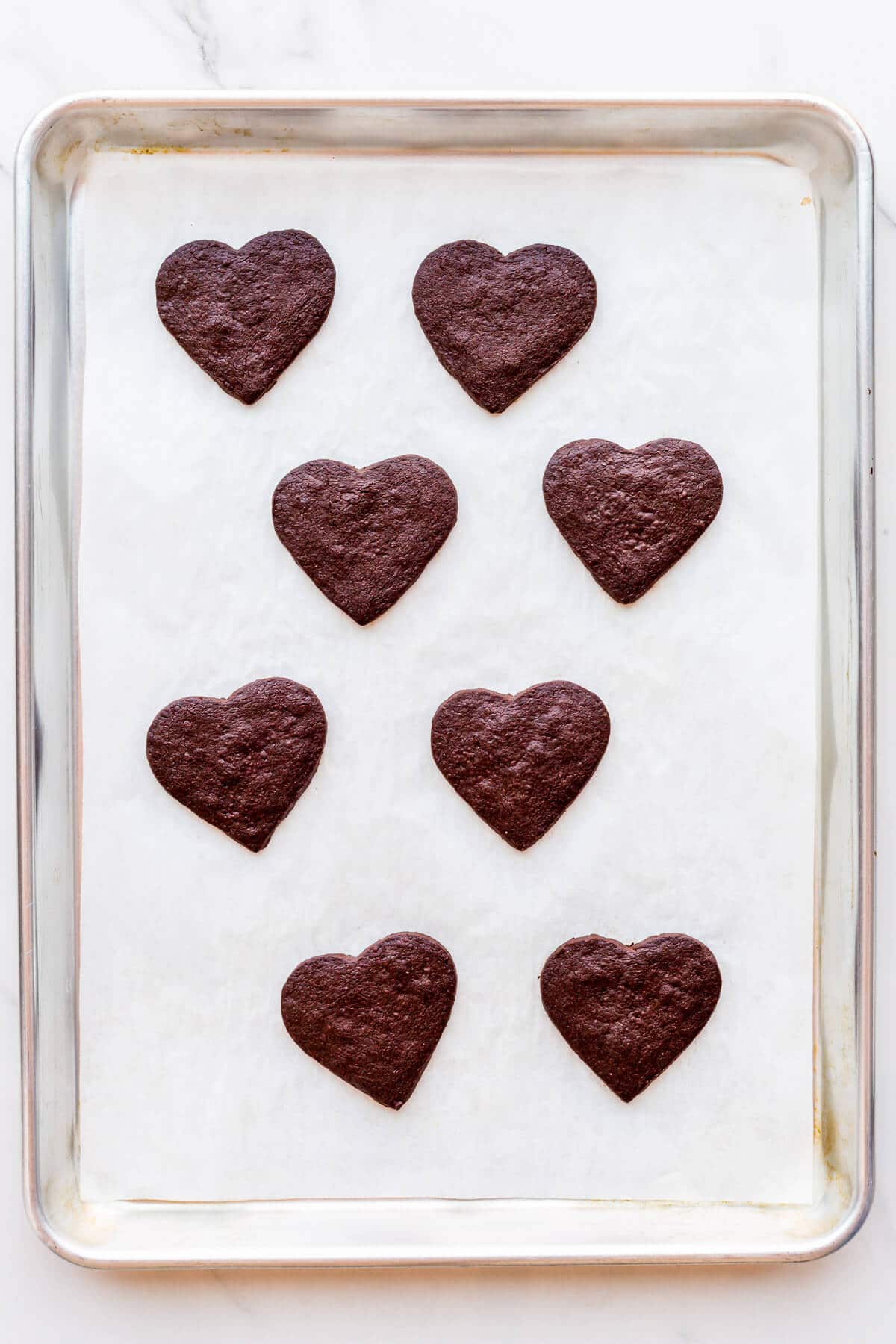 Chocolate shortbread cookies after baking on a sheet pan.