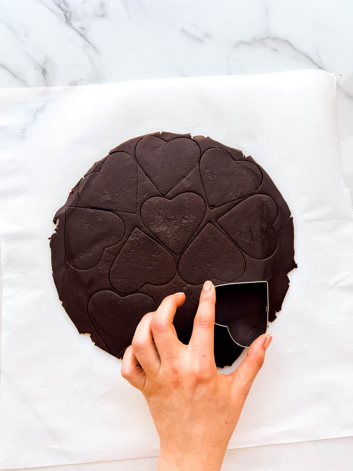 Cutting out rolled chocolate dough to make chocolate butter cookies.