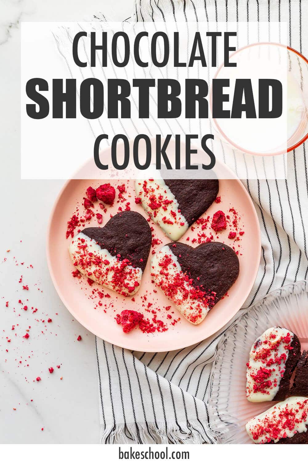 A plate of chocolate shortbread cookies that are dipped in white chocolate and sprinkled with crushed freeze-dried raspberries.